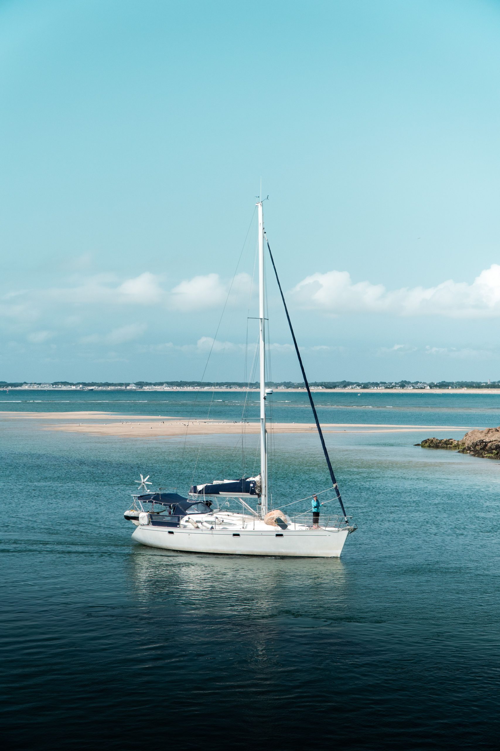 A serene scene of a yacht sailing on a calm ocean under a clear blue sky.