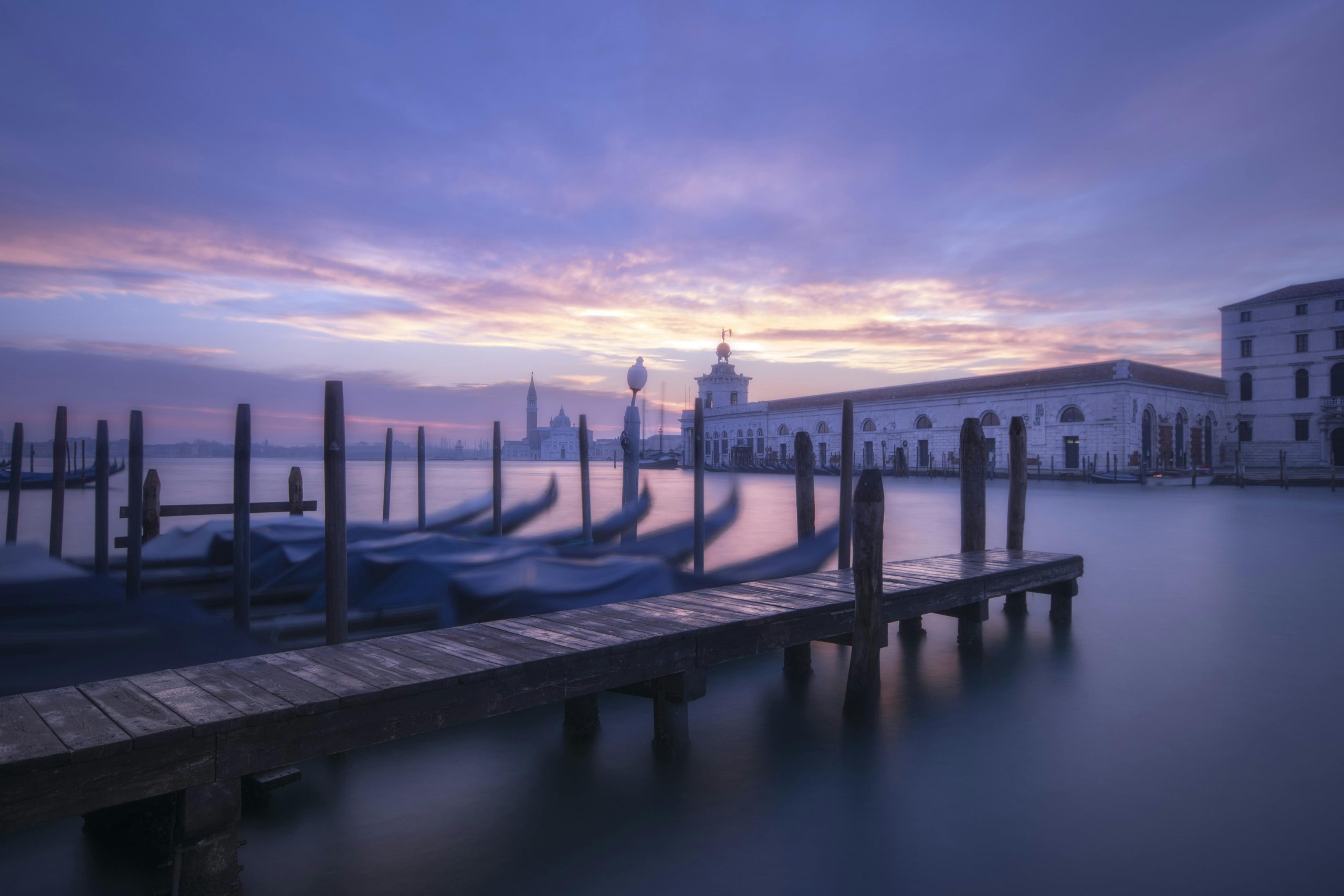 Captivating view of Venice gondolas at dusk with a vibrant sky reflecting on serene waters.