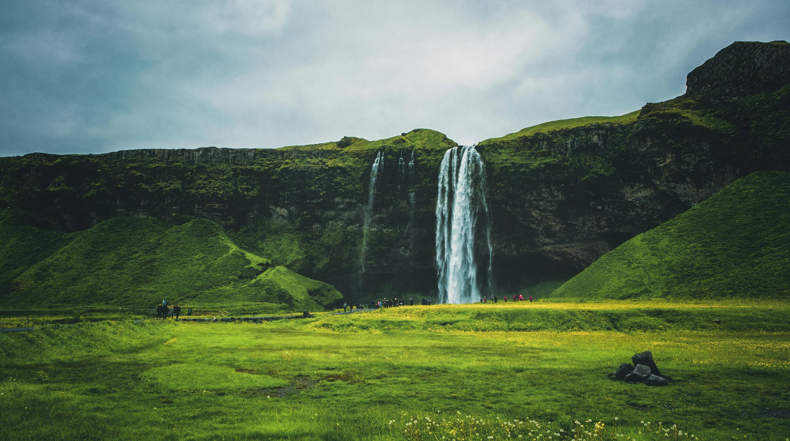 Scenic view of a majestic waterfall cascading over green cliffs in Iceland.