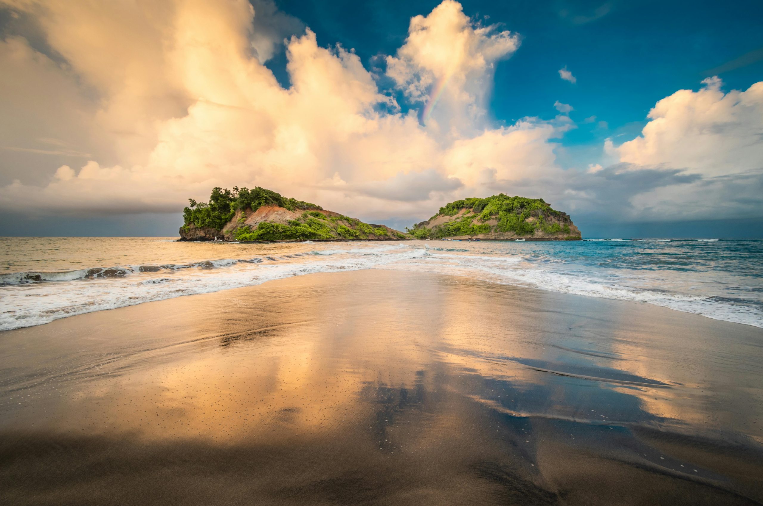 A stunning view of two lush islands off the coast of Sainte-Marie, captured at sunset with reflections on the sand.