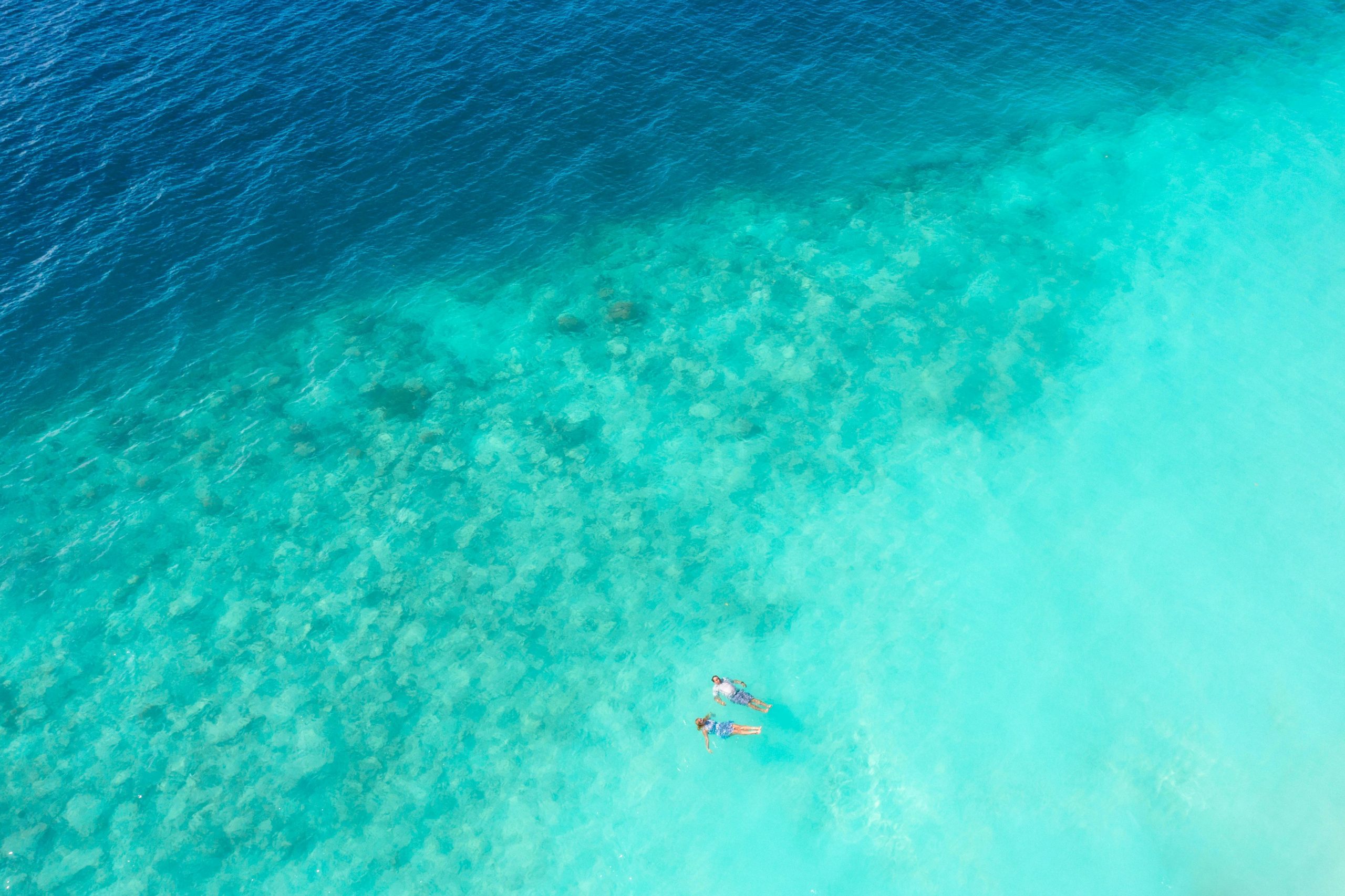 Beautiful aerial shot of a couple swimming in the turquoise waters of Maldives, perfect for vacation themes.