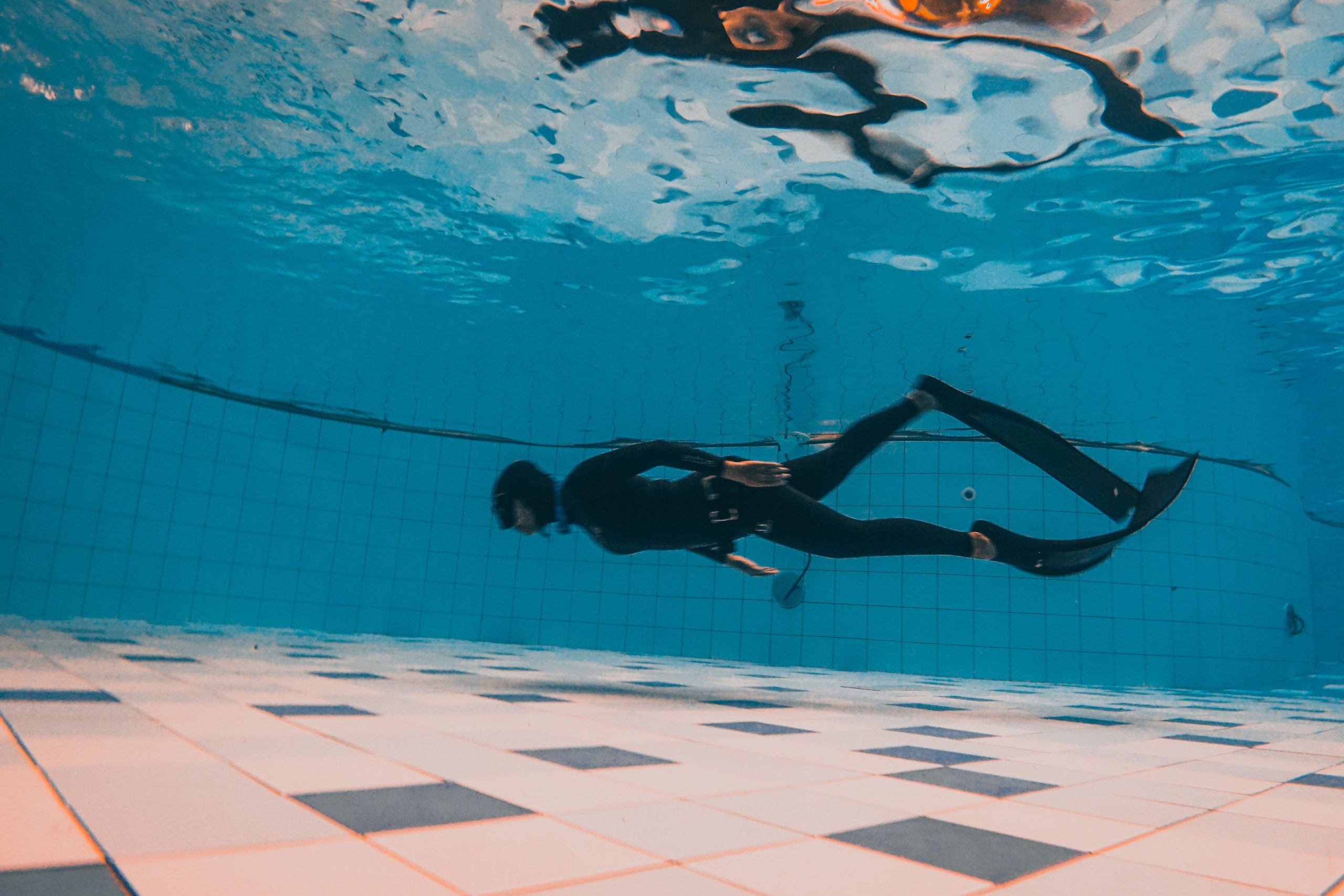 Deep dive under a swimming pool with a diver exploring the underwater world.