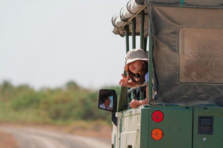 Young girl enjoying a safari ride in an open-top vehicle, exploring the wilderness.